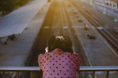 İntihar önleme konsepti tren istasyonunun yakınındaki köprüde duran depresyondaki genç Asyalı kadın, olumsuz tavır.
