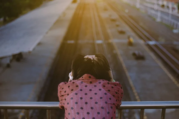 İntihar önleme konsepti tren istasyonunun yakınındaki köprüde duran depresyondaki genç Asyalı kadın, olumsuz tavır.