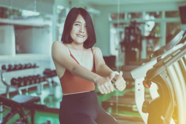 Formda Asyalı bir kadının spor salonundaki eğitimden sonra baş parmağını göstermesi ve dinlenmesi, kadın egzersiz ve egzersizden sonra ara vermesi, sağlıklı ve yaşam tarzı kavramı, seçici odaklanma.