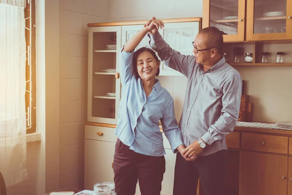 Kıdemli Asyalı çift dans ediyor, evde birlikte eğleniyor, sonsuza dek aşk ve eğlence içinde yaşıyor.