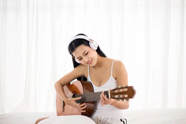 幸せなアジアの女性の手演奏ギターでベッドルームで朝 リラックスした時間 — ストック写真