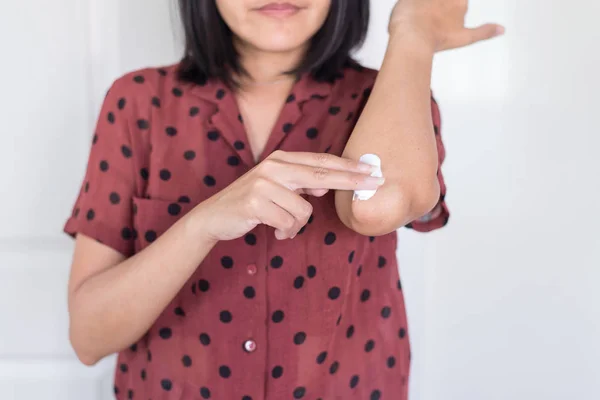 Asian woman applying cream or lotion on dry elbow, Healthy skin body care concept