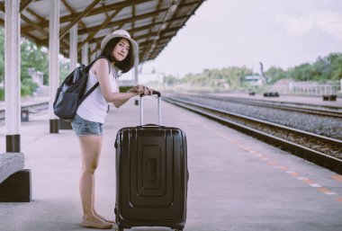 Hippi güzel Asyalı kadın tren istasyonunda bekliyor, mutlu ve gülümsüyor, seyahat ve tatil konsepti.