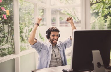 Başarılı bir adam ellerini kaldırdı ve online olarak maçı kazandı, mutlu ve gülümsüyor, dinlenme zamanı.