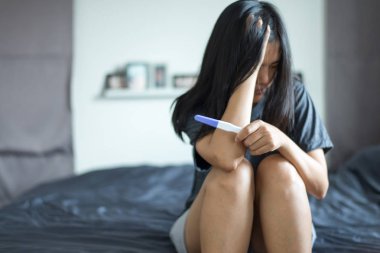 Asian depressed female sitting in her bedroom after testing pregnancy test,Selective focus clipart