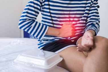 Yemekten sonra karnı ağrıyan bir kadın, karnını tutan bir kadın, gıda zehirlenmesi, sindirim sorunları.