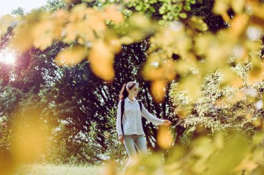 Güzel genç bir kadın sabah parkta yürüyor, mutlu ve gülümsüyor, dinleniyor, pozitif düşünüyor.