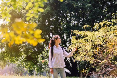 Güzel genç bir kadın sabah parkta yürüyor, mutlu ve gülümsüyor, dinleniyor, pozitif düşünüyor.