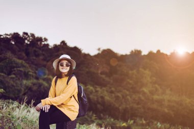 Hippi kız oturuyor ve doğaya bakıyor, olumlu düşünüyor, açık havada seyahat ediyor ve boş zaman kavramını kullanıyor.