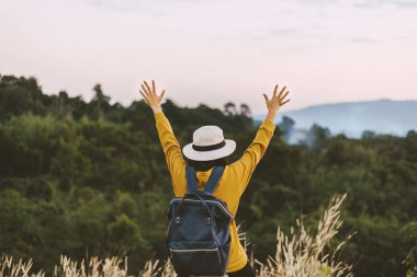 Genç hippi kız ayakta duruyor ve doğaya bakıyor, olumlu düşünüyor, açık havada seyahat ediyor ve boş zaman kavramını kullanıyor.