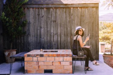 Güzel Asyalı kadın kafede otururken cep telefonu kullanıyor, mutlu ve gülümsüyor, dinleniyor, pozitif düşünüyor.