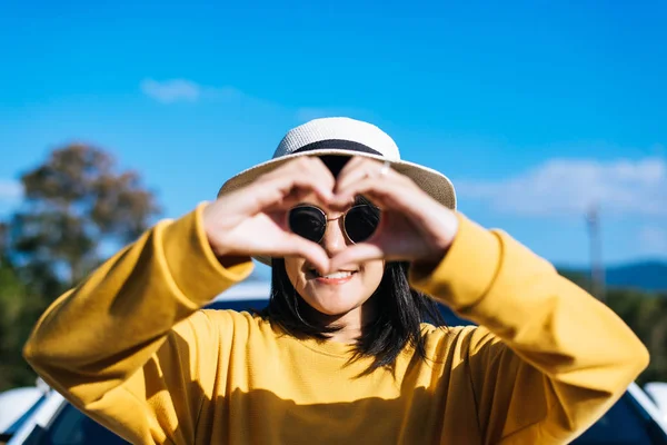 Happy asian woman standing and showing hands heart shape at nature,Happy and smiling,Positive thinking,Back view