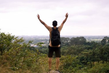 Tourist man with hands raised up and looking beautiful view feeling happy and smiling at nature,Back view