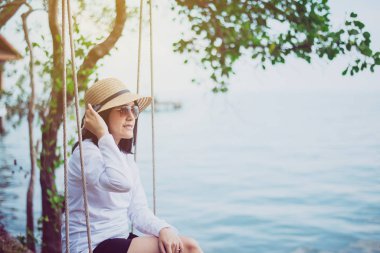 Güzel Asyalı kadın salıncakta sallanıyor, mutlu ve gülümsüyor, dinleniyor