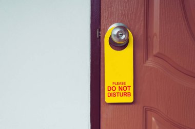 Closed door with please do not disturb sign on handle of hotel room