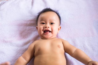 Sevimli Asyalı erkek bebek yatağa uzanıyor, mutlu ve gülümsüyor, çocukluk ve bebek bakımı kavramı.
