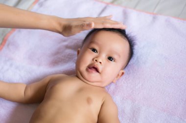 Sevimli Asyalı erkek bebek yatağa uzanıyor, anne özen ve destek veriyor, çocukluk ve bebek bakımı kavramı.