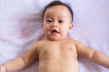 Sevimli erkek bebek yatak odasında uzanıyor, mutlu ve gülümsüyor, çocukluk ve bebek bakımı kavramı.