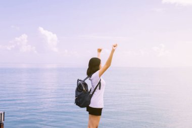 Happy young asian woman standing with hand raise up at sea,Enjoying in Nature,Freedom concept