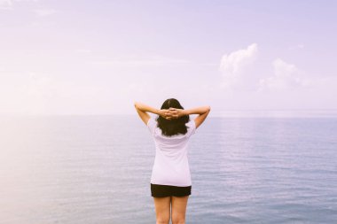 Denizde elleri havada mutlu bir kadın, Doğa ve Özgürlük kavramının tadını çıkarıyor.