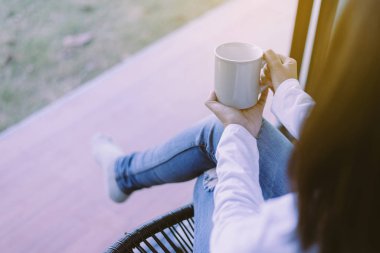 Yatak odasında bir fincan kahve tutan bir kadının ellerini kapatın, rahatlatıcı sabah, sağlıklı ve yaşam tarzı konsepti