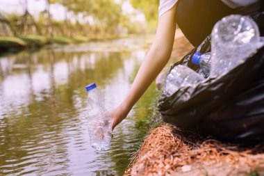 Nehirde plastik çöp toplayan gönüllü bir kadın çevre ve kirlilik kampanyası konsepti