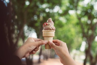 Kadın elleri çikolatalı waffle külahı kalorilerini hafif arka planda tutuyor.