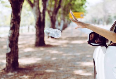Kadın eli plastik şişe çöplerini yola atıyor, Çevre ve kirlilik kampanyası konsepti