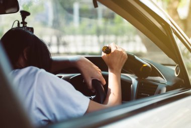 Sarhoş Asyalı kadın araba kullanırken alkol içiyor, kadınlar arabasını bira şişesiyle kullanıyor, tehlikeli sürüş konsepti var.