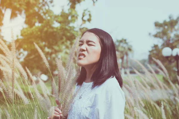 Asian woman sneezes because of allergy with flower at outdoor