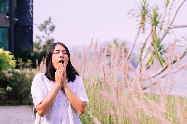 Beautiful asian woman sneezes because of allergy with flower at nature