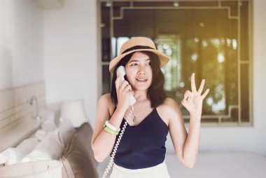 Yatak odasında telefonu kullanan güzel Asyalı kadının portresi olumlu düşünce, iyi tavır, mutlu ve gülümseyen