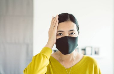 Maske kullanan Asyalı kadın Başbakan 2.5 'u koruyor çünkü evdeki kirlilik, genç bayanın baş ağrısı ve burun alerjisi var.