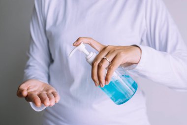 Kadın elleri, el hijyen koronavirüsü koruması için pompa şişesinde dezenfektan jeli kullanıyor.