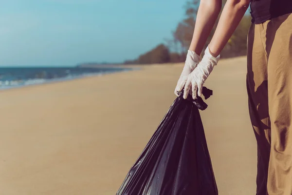 Volunteer asian woman holding black color garbage bag with keeping plastic bottle at the beach,Dispose recycle and waste management concept,Good conscious mind