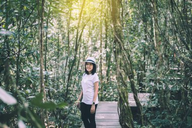 Genç Asyalı kadın yağmur ormanlarında yürüdükten sonra dinleniyor.