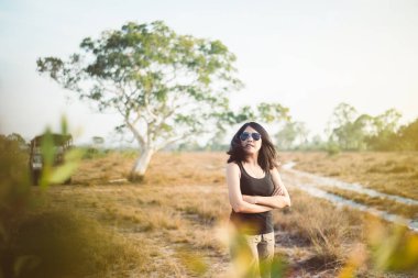 Mutlu Asyalı genç kadın gezgin gün batımında Savana 'da durup kollarını kavuşturdu dinlendirici ve boş zaman, seyahat ve tatil konsepti