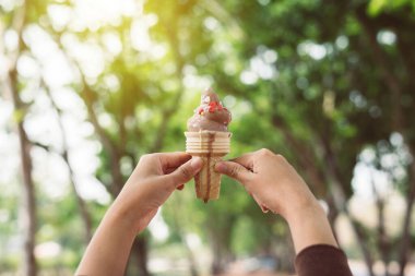 Açık yeşil arka planda çikolatalı waffle külahı kalorisi tutan eller.