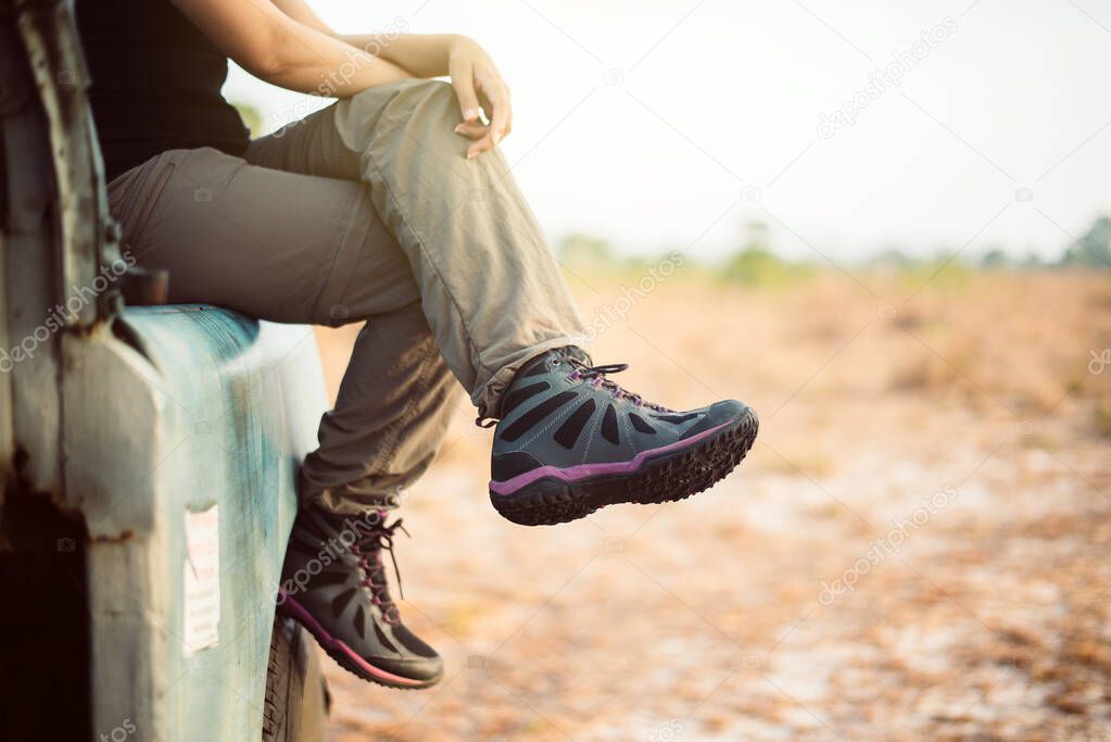 Woman traveller sitting on car at nature,Hiking shoes woman in beautiful view,Road trip