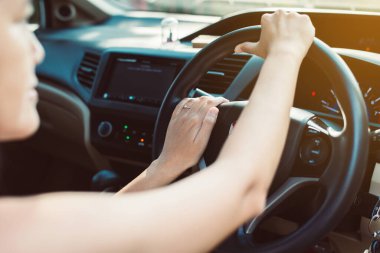 Elleri direksiyonda, araba süren bir kadın.