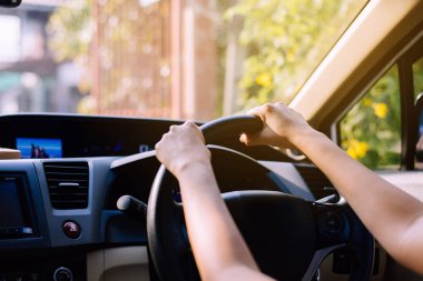 Elleri direksiyonda, araba süren bir kadın.