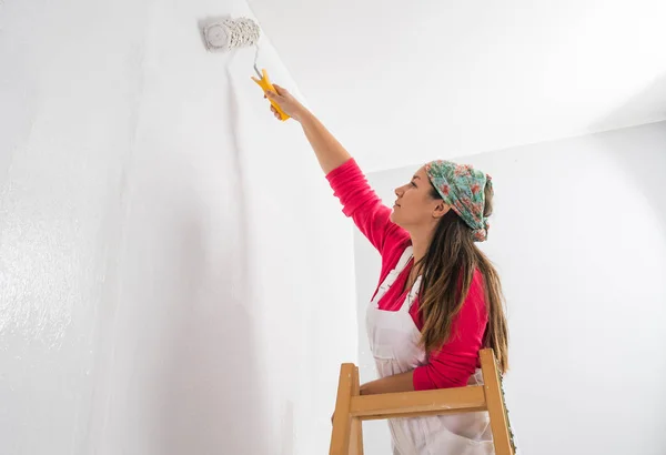 壁を塗る梯子の上に立っている若い女の子 — ストック写真