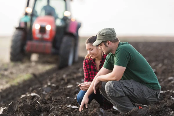 Agricoltori che esaminano la sporcizia mentre il trattore aratura campo — Foto Stock