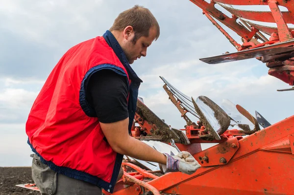 Mechanic fixing plow on the tractor — Stock Photo, Image