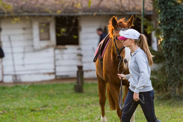 Mladá dívka, příprava koně pro jízdu — Stock fotografie