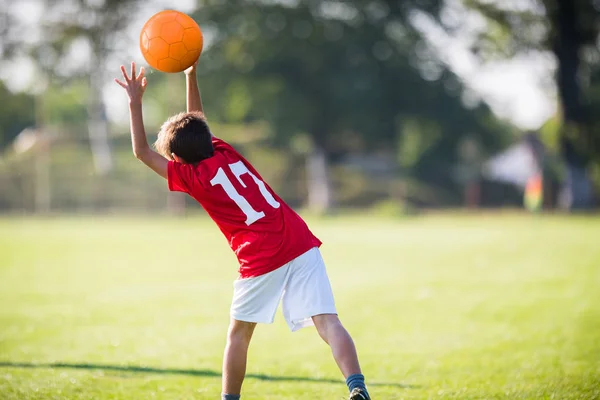 Niño jugador de fútbol lanza la pelota en el partido — Foto de Stock