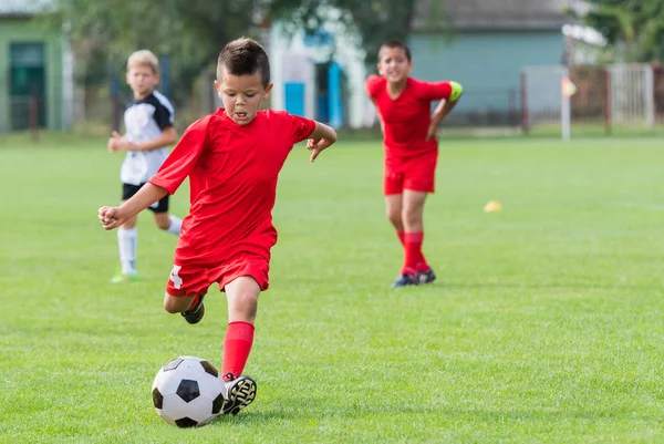 Rapaz chutando bola de futebol — Fotografia de Stock