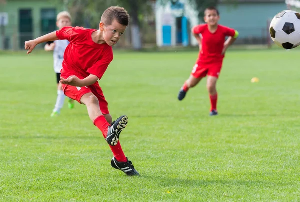 Rapaz chutando bola de futebol — Fotografia de Stock
