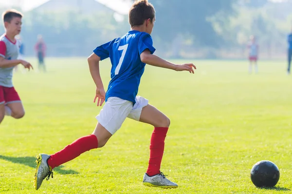 Rapaz chutando bola de futebol — Fotografia de Stock