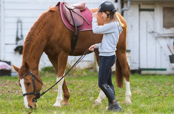 Young girl preparing horse for ride — Stock Photo, Image